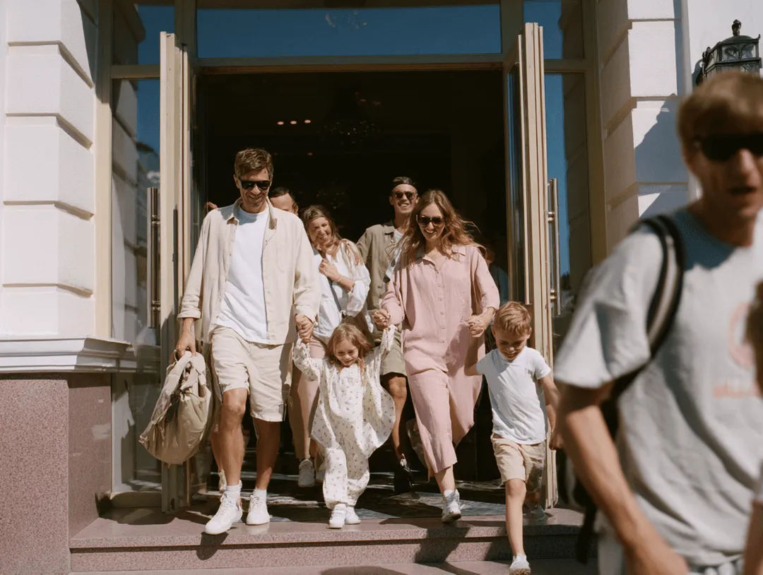 Eine glückliche Familie die gerade aus ihrem Hotel stürmt voller Vorfreude auf den kommenden perfekten Tag in ihrem Urlaub.